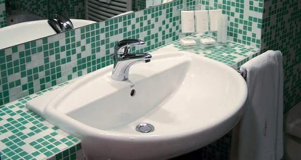 A bathroom with a white sink, green and white checkered tiles, and a mirror above the sink. - Hotel Don Guglielmo (Campobasso)
