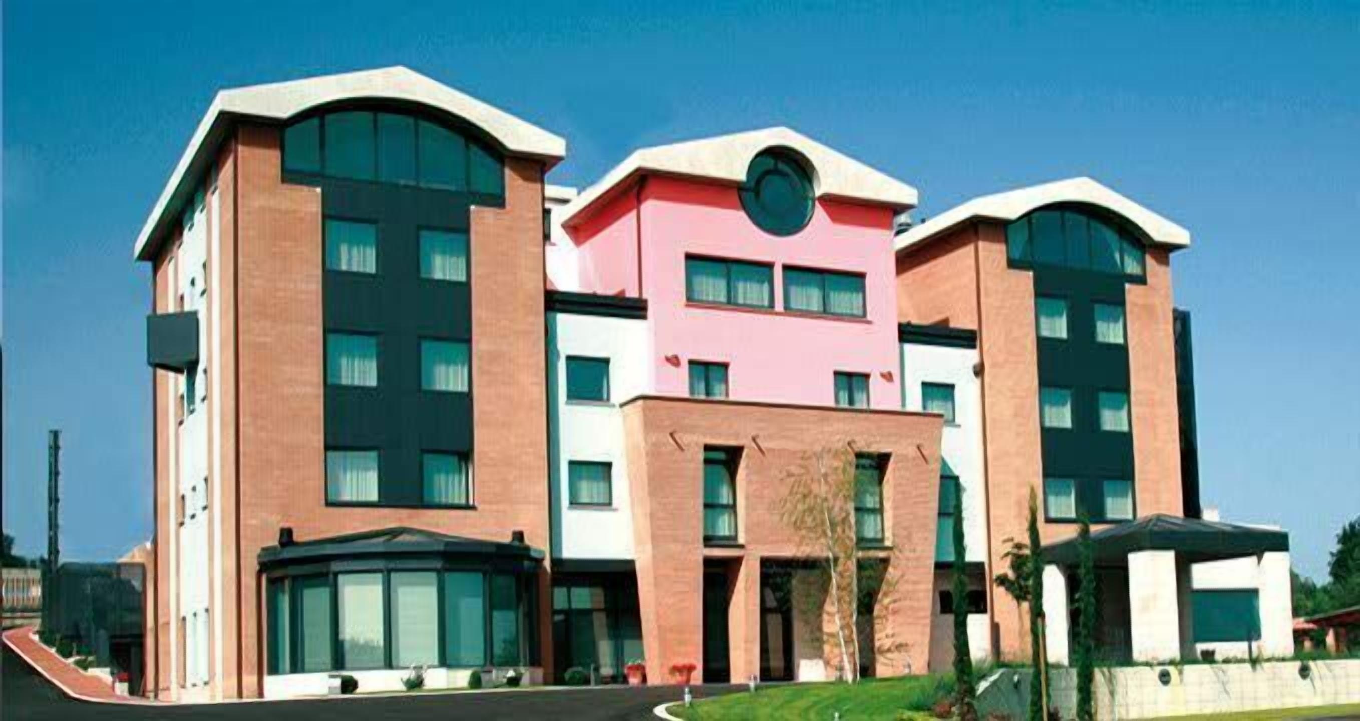 Un immeuble moderne à plusieurs étages, avec une façade combinant briques et verre, de grandes fenêtres et une entrée centrale.