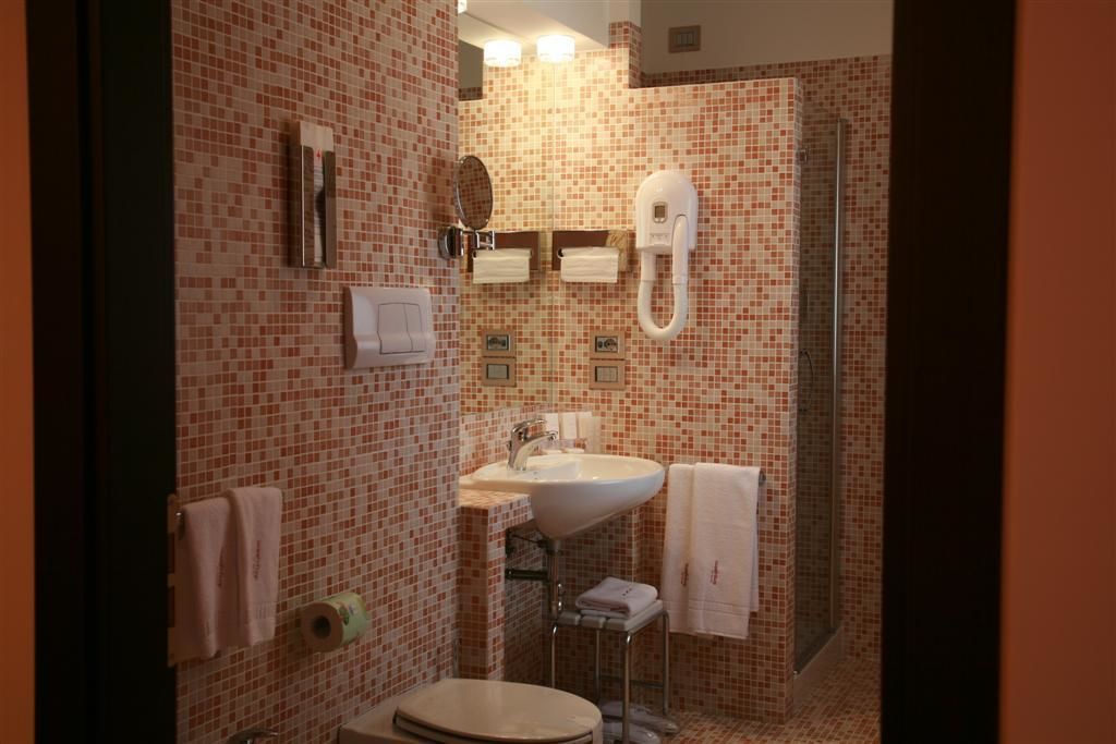 A bathroom with a tiled floor, a sink, a toilet, and a shower.