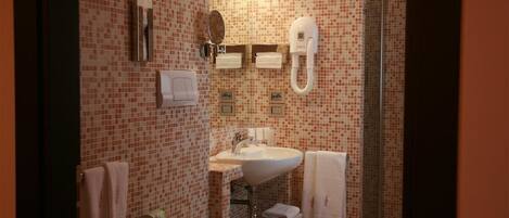 Un baño con piso de baldosas, un lavamanos, un inodoro y una ducha.