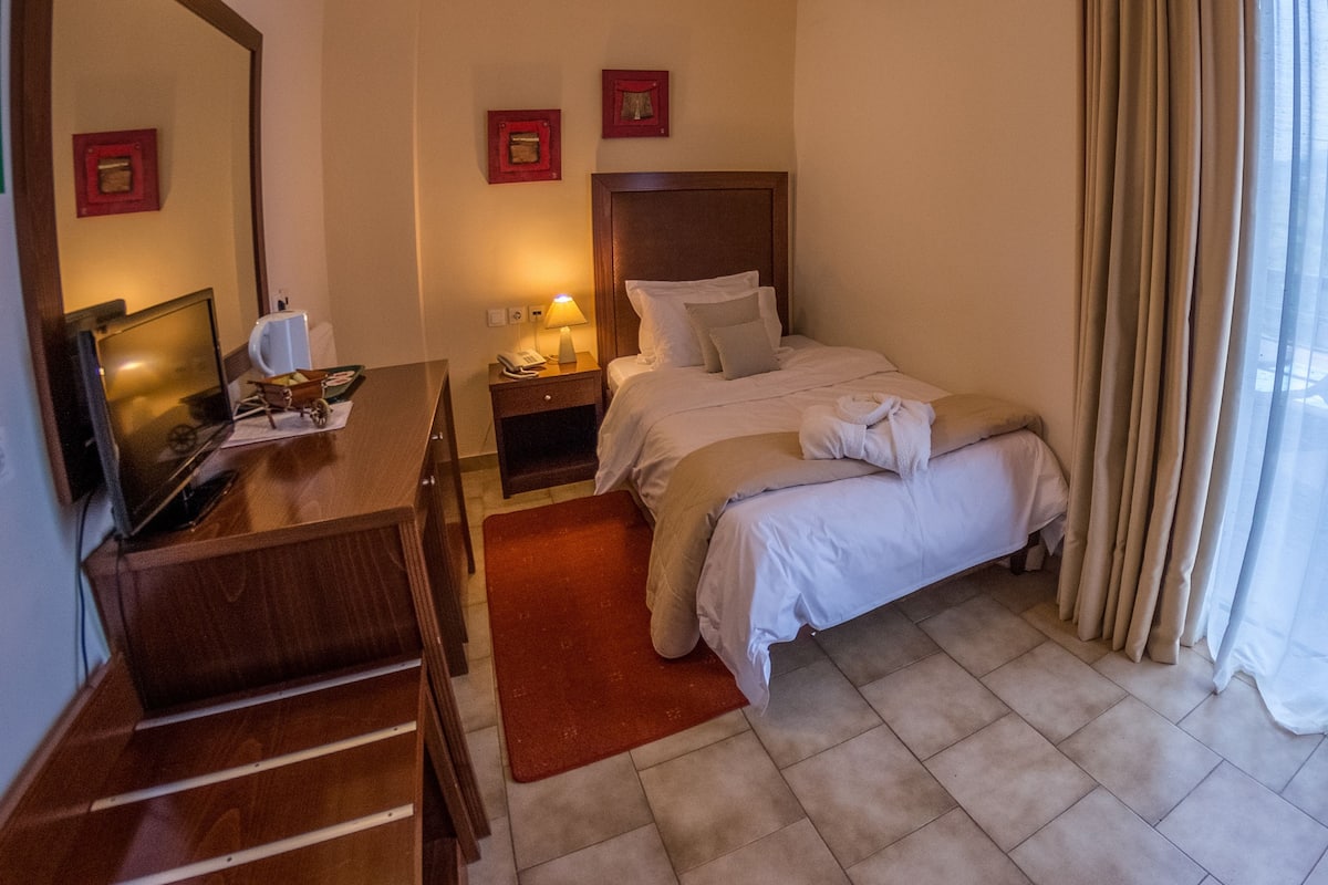 A hotel room with a bed, a desk, a TV, and a nightstand.
