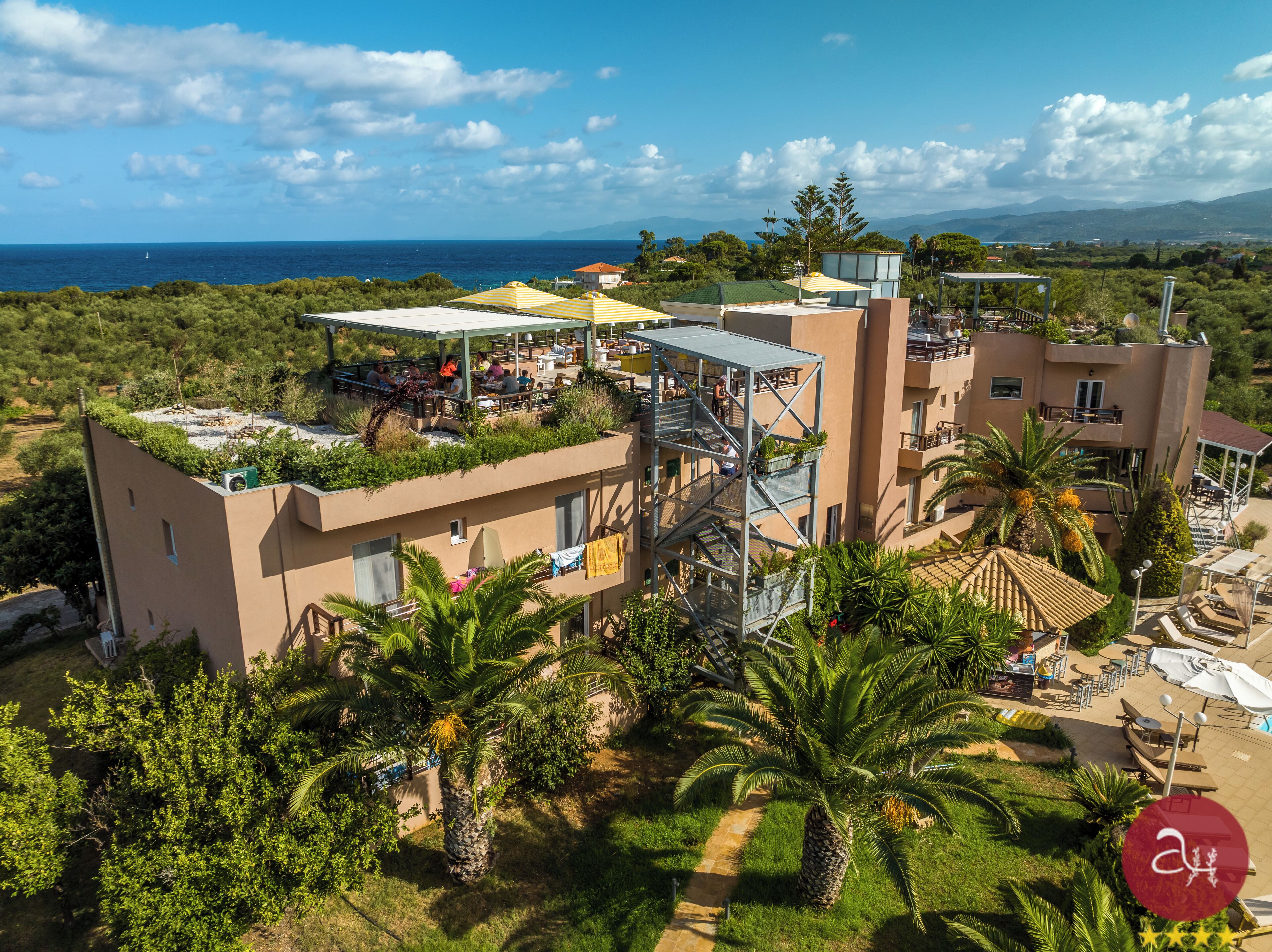 A modern hotel with a rooftop terrace, outdoor seating, and a view of the sea.