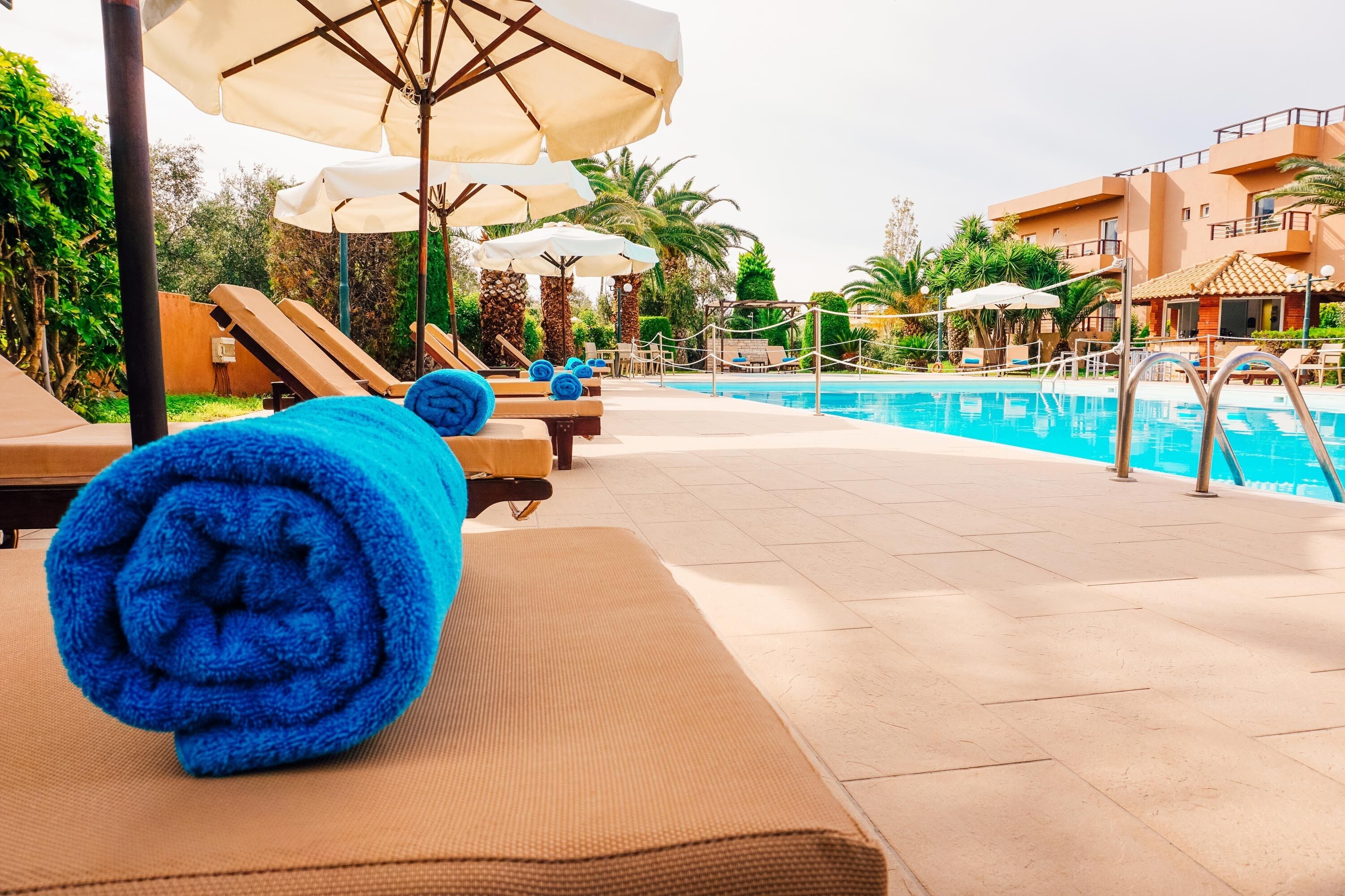 A poolside area with sun loungers, towels, and umbrellas.