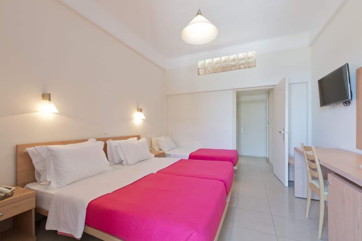 A hotel room with a large bed, bedside tables, a desk, and a television.