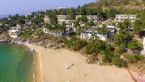 Una zona residencial costera con edificios modernos de varios pisos, una playa de arena y aguas azules cristalinas.
