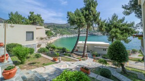 Una propiedad costera con terraza de piedra, plantas en macetas y vista al mar.
