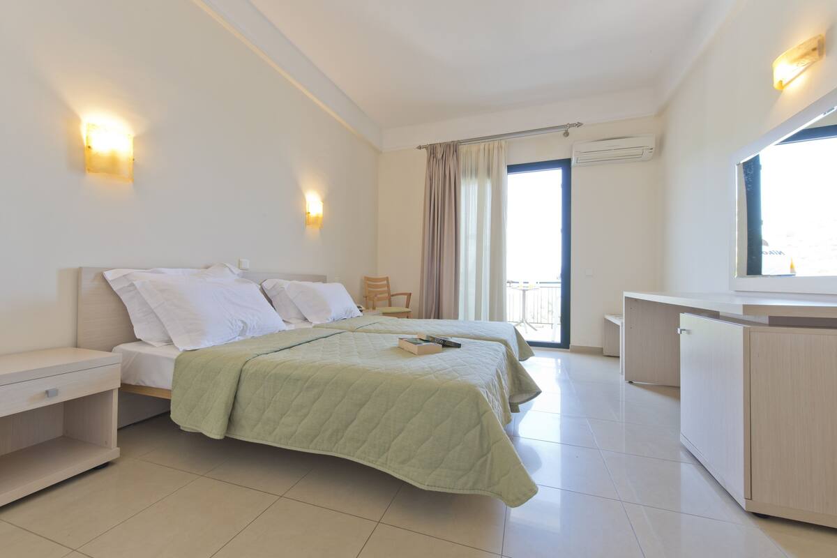 A modern hotel room with two beds, a desk, and a balcony.