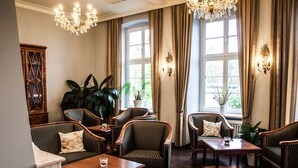 Ein Zimmer mit Holzböden, gestreiften Polsterstühlen, einem Marmortisch und einer Chandelier.
