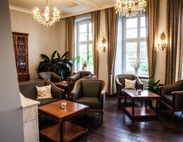 Quarto com piso de madeira, cadeiras estofadas com padrão listrado, mesa com ladrilhos de mármore e um candelabro.