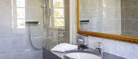 A modern bathroom with a large mirror, a sink, and a shower.
