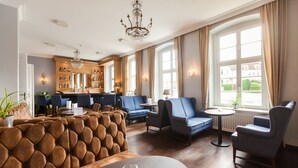 Eine großzügige Hotelhalle mit Barbereich, Sitzgelegenheiten und großen Fenstern, die für natürliches Licht sorgen.