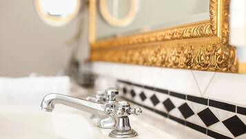 A bathroom with a white sink, chrome faucets, and a gold-framed mirror.