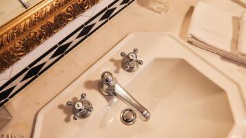 A bathroom sink with two faucets, a mirror, and a towel stack.