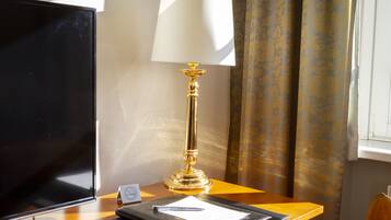 Una habitación de hotel con escritorio, televisión, lámpara, bloc de notas y bolígrafo.