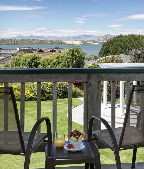A balcony with a table set for breakfast, overlooking a lake and mountains. - Sea Pines Resort (Los Osos)
