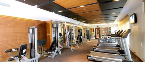 A gym with treadmills, weight machines, and a mirrored wall.