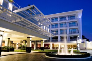 Un hôtel moderne à l’architecture imposante, doté d’une structure à plusieurs étages, d’un espace extérieur abrité et d’une fontaine centrale.