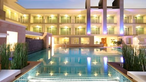 A hotel with a large indoor swimming pool, multiple balconies, and a well-lit facade.