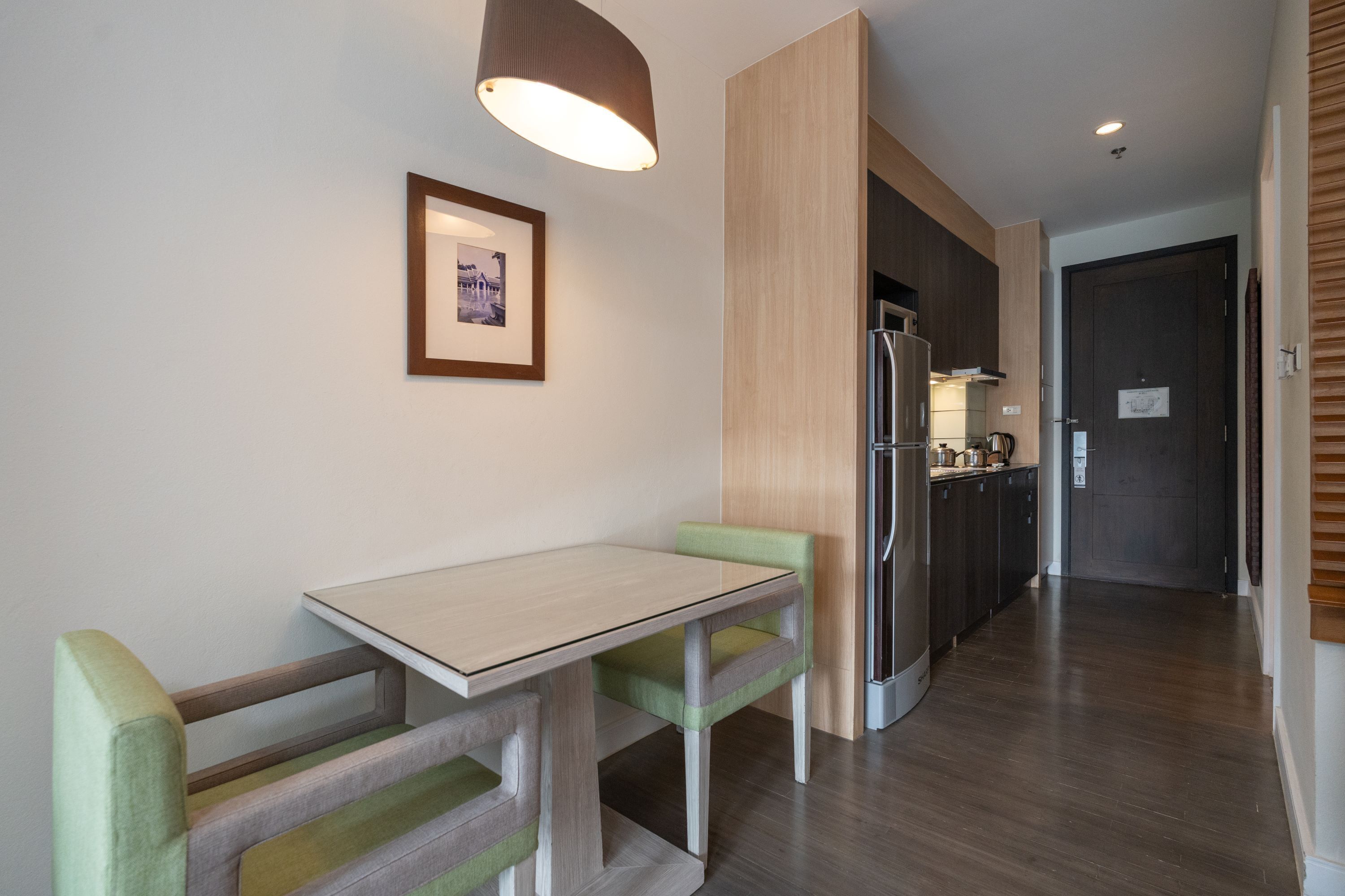 A modern kitchen with a built-in refrigerator, wooden cabinets, and a dining area with a table and chairs.