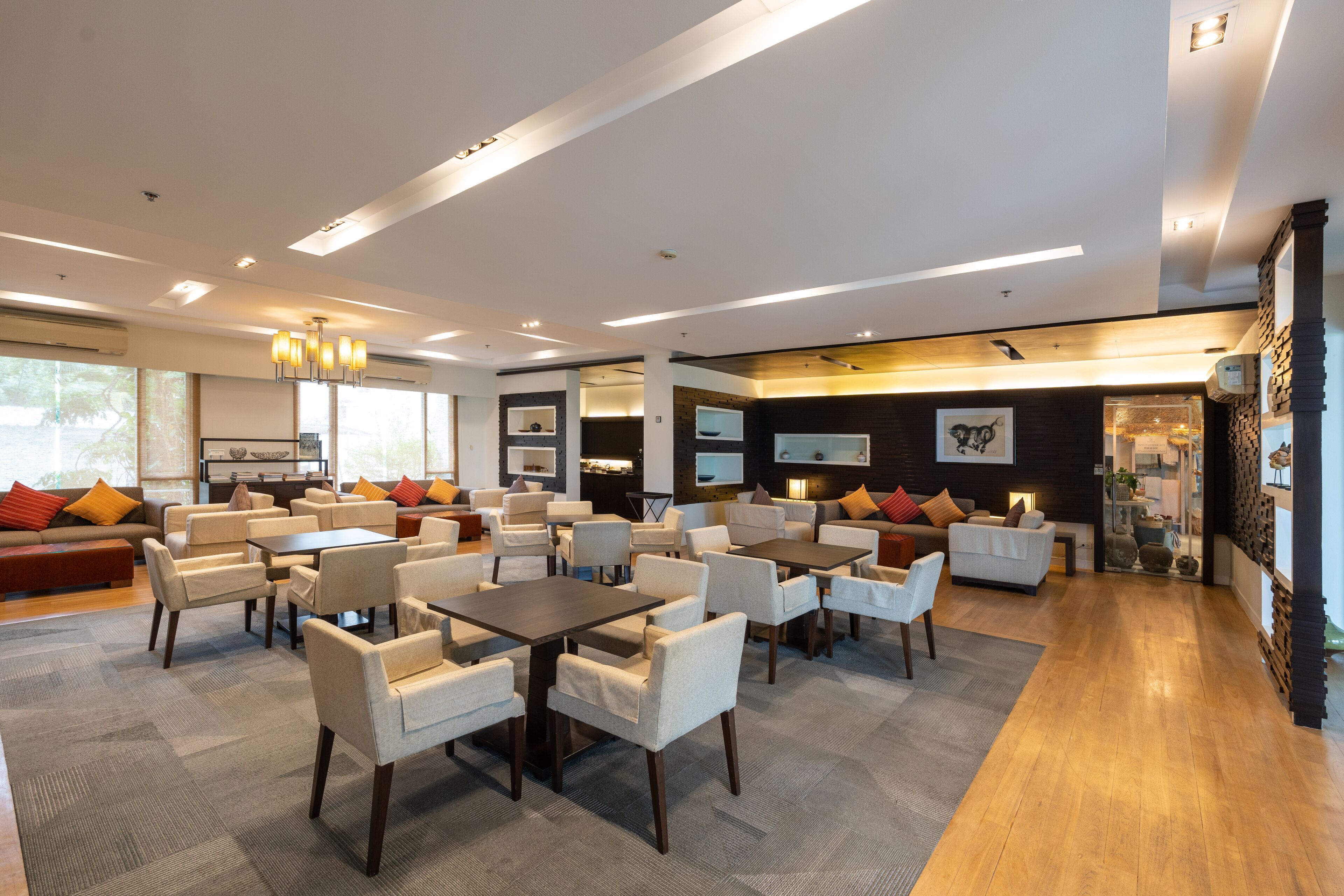 A spacious hotel lobby with multiple seating areas, including sofas and tables, and a large television screen.