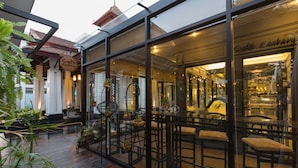 A café with outdoor seating, a wooden deck, and potted plants.