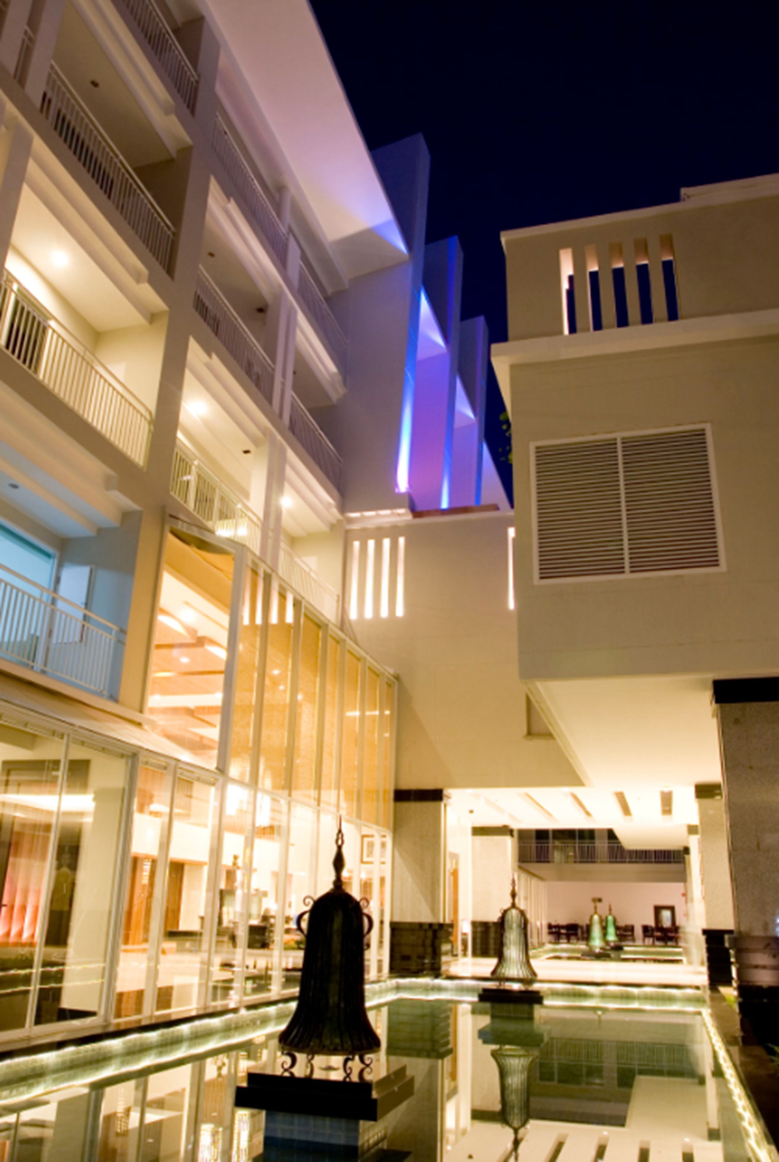 Eine moderne Hotelhalle mit Glasatrium, einer Fontäne und einem Poolbereich.