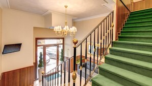 A staircase with green carpet and black balusters, leading to a second floor. - Hotel Flavio Rome (Rome)