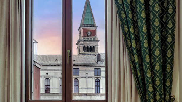 A window with a view of a building with a clock tower and a dome.