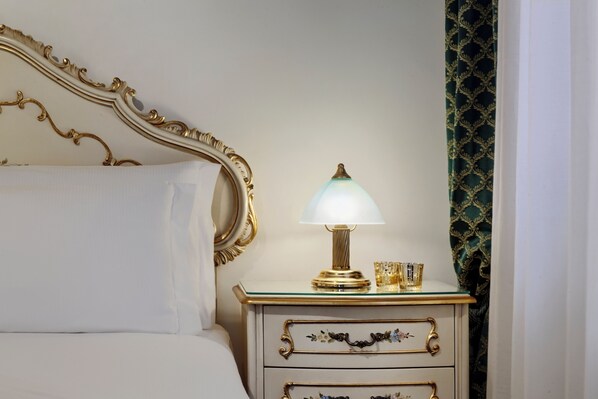 A bed with a white headboard, a bedside table with a lamp, and a patterned curtain.