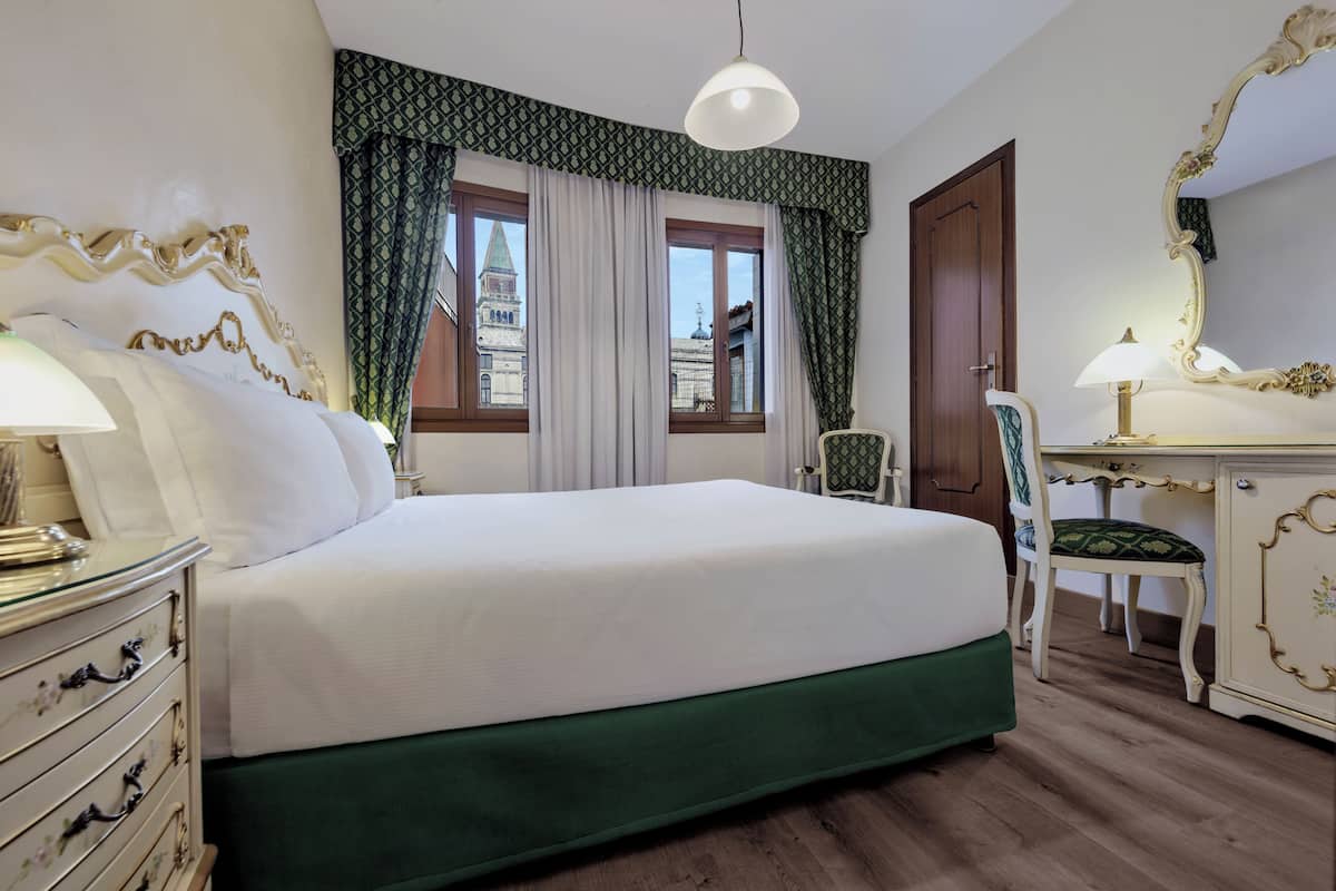 Een hotelkamer met een bed, een bureau, een stoel en een grote spiegel.