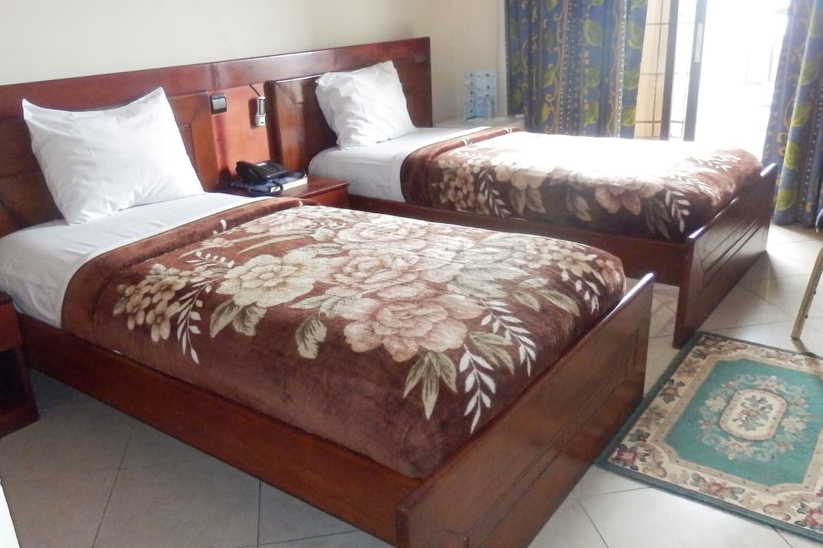 A double bed with a floral bedspread, a bedside table with a phone, and a nightstand.