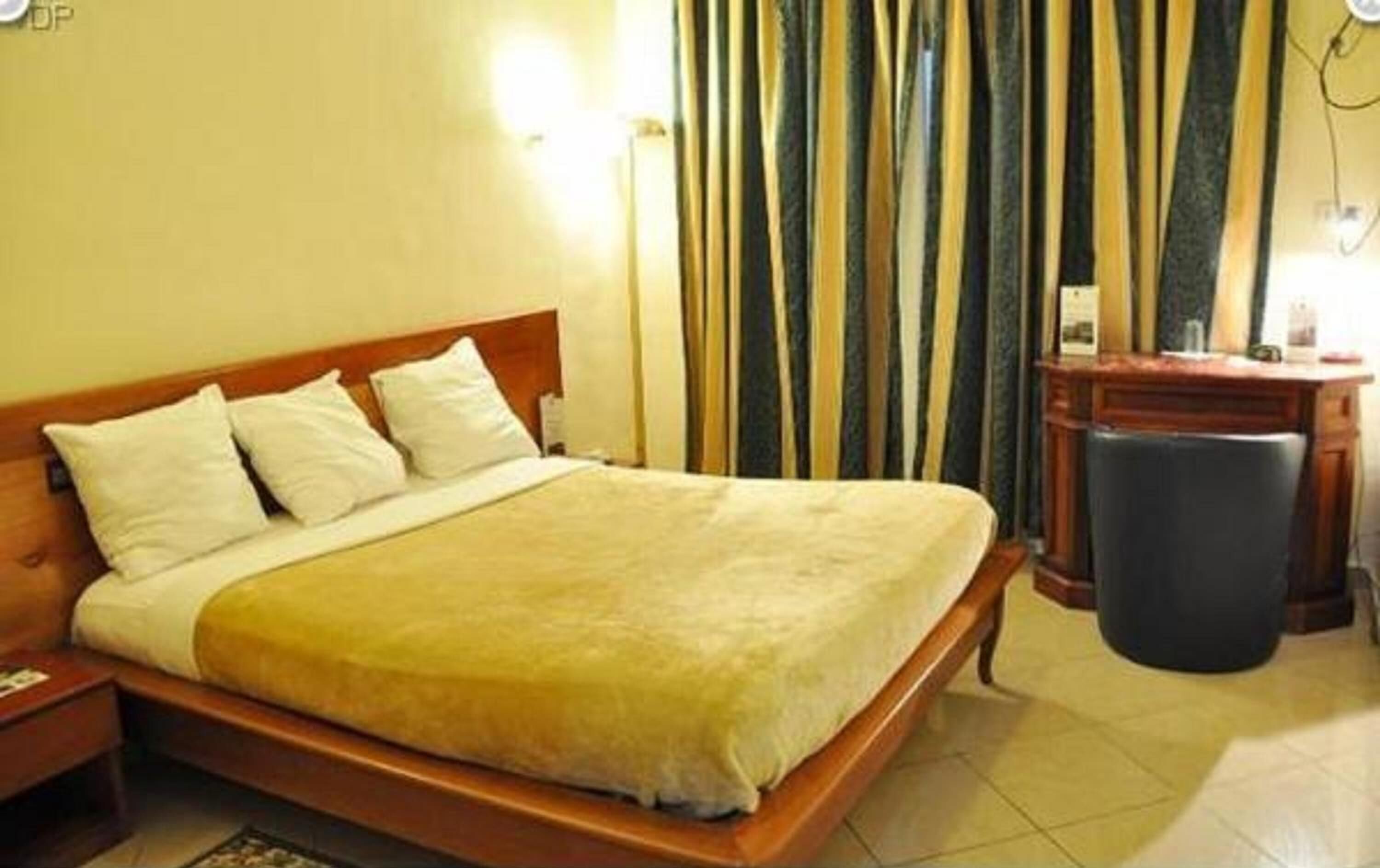 A standard hotel room with a single bed, a nightstand, a desk, and a trash bin.