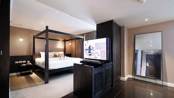 Ein modernes Hotelzimmer mit Himmelbett, Flachbildfernseher, Minibar und großem Spiegel.