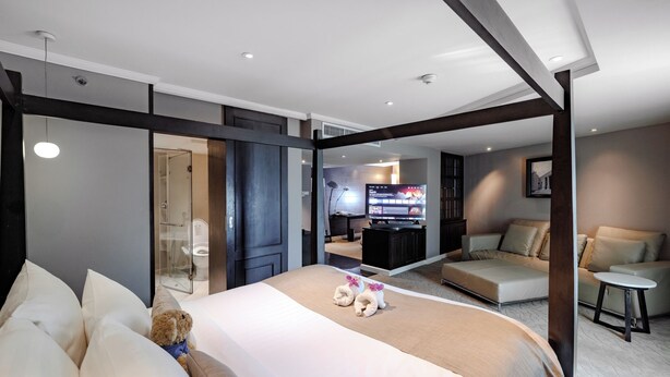 Una habitación de hotel moderna con una cama grande, televisor, zona de estar y baño.