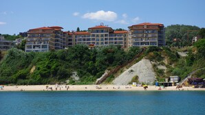 A coastal hotel with multiple buildings, a sandy beach, and a staircase leading up to the buildings. - Byala Beach Resort (Byala)