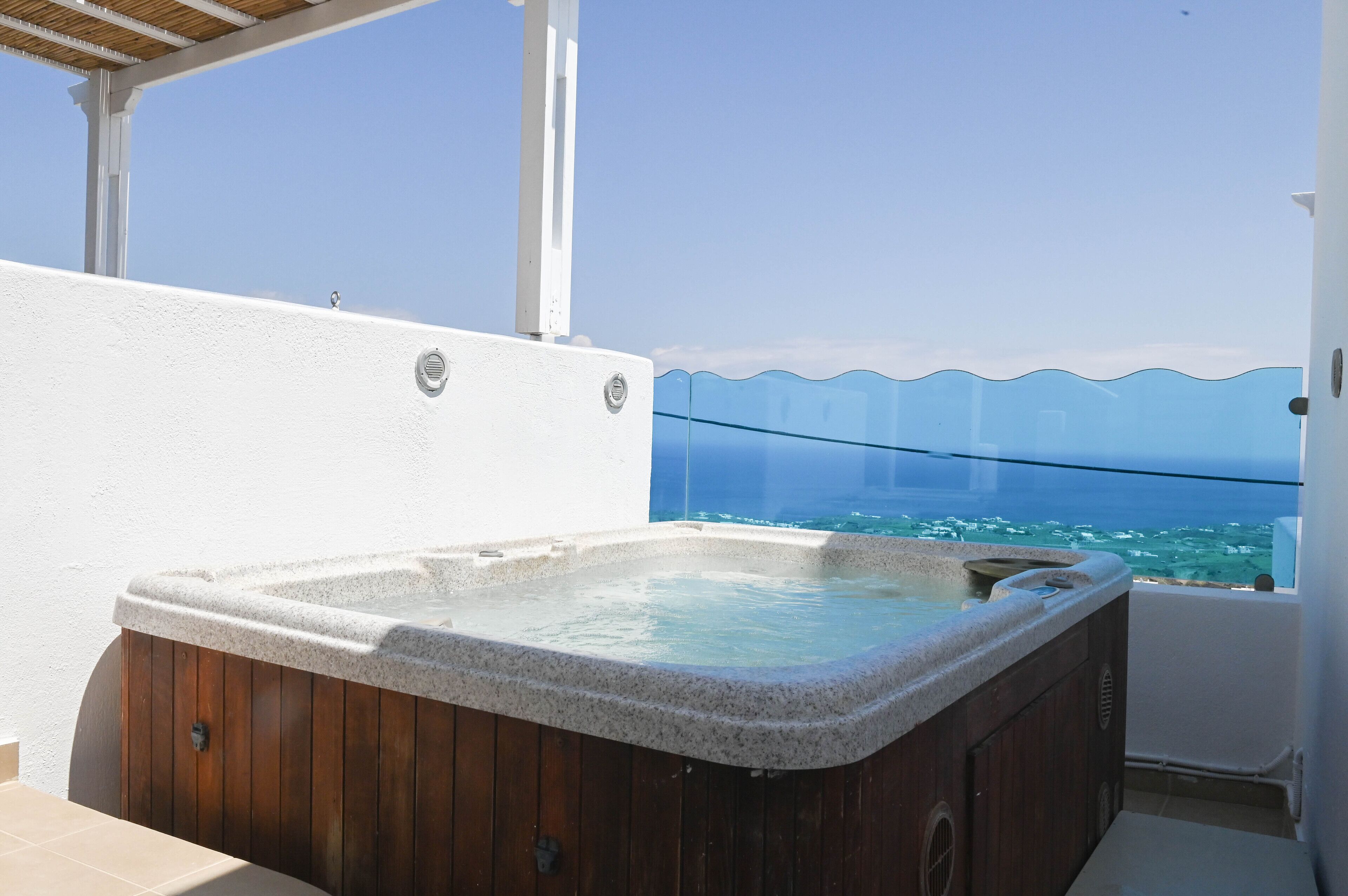 Un jacuzzi en un balcón con vista despejada al mar.