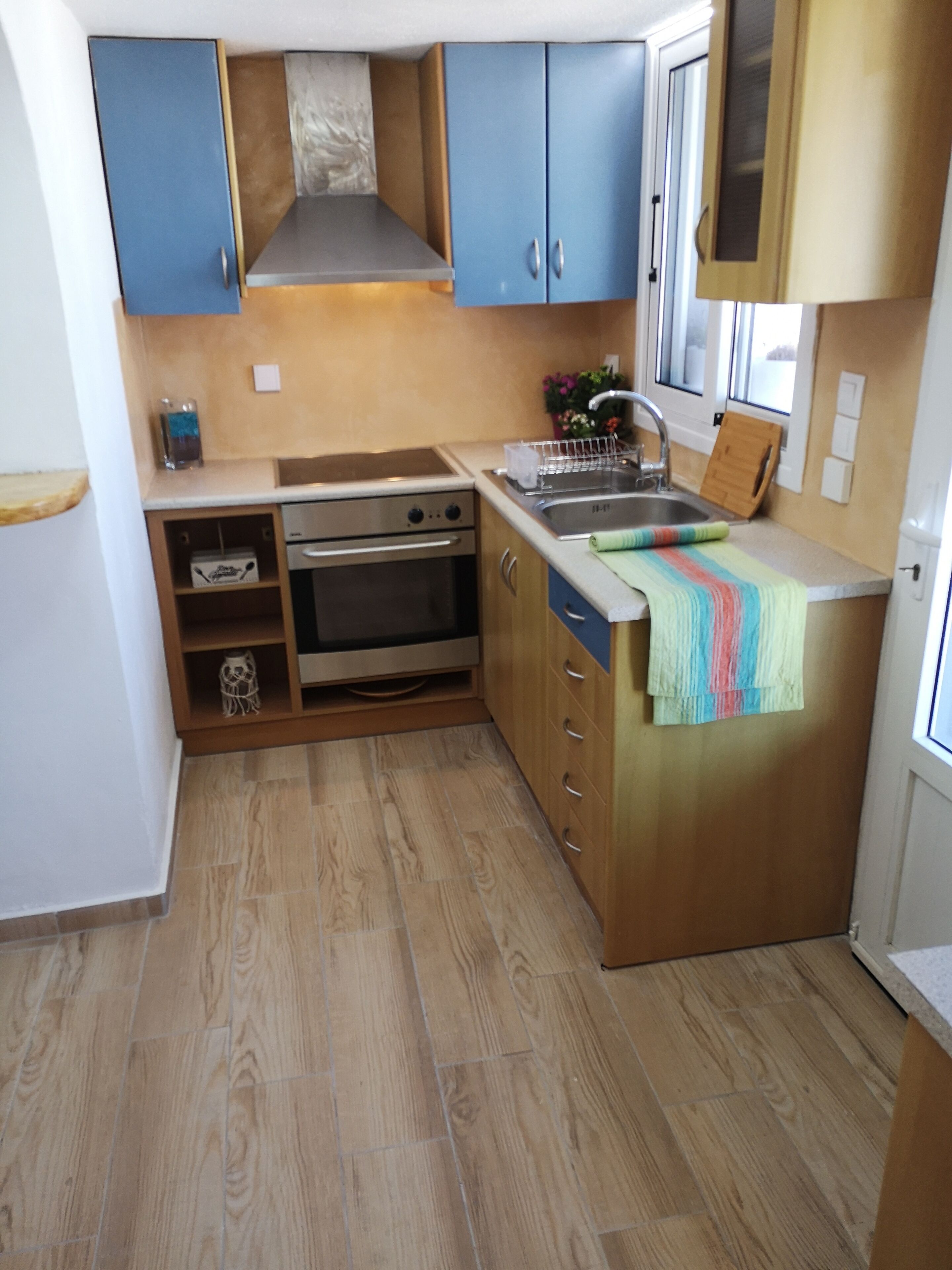 A compact kitchen with blue cabinets, a stainless steel sink, and a wooden countertop.