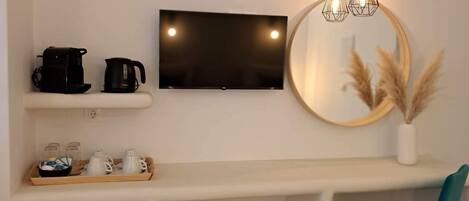 A modern kitchen with a built-in fridge, a coffee maker, a kettle, and a TV mounted on the wall.