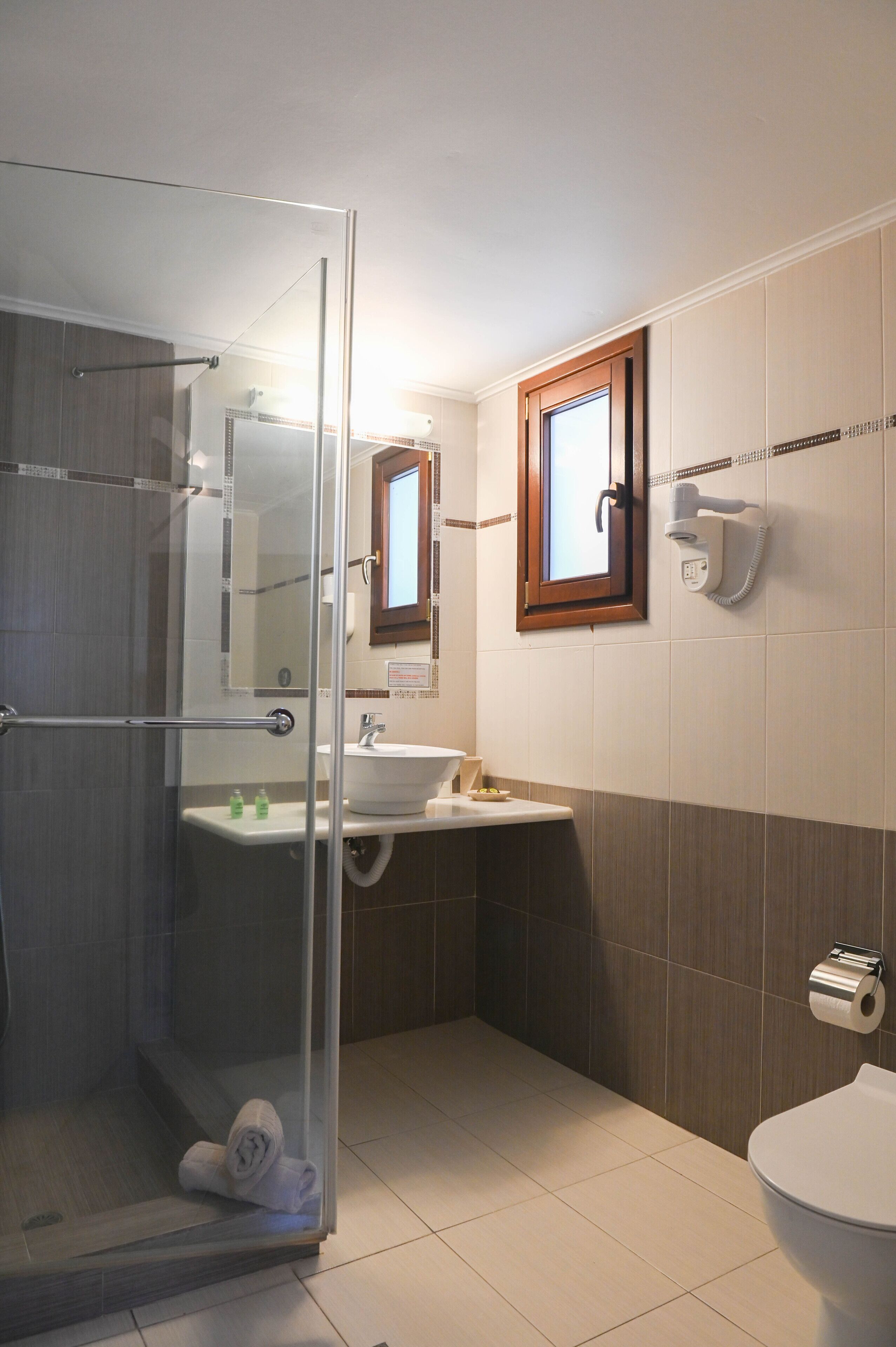 A modern bathroom with a glass shower enclosure, a sink with a mirror, and a toilet.