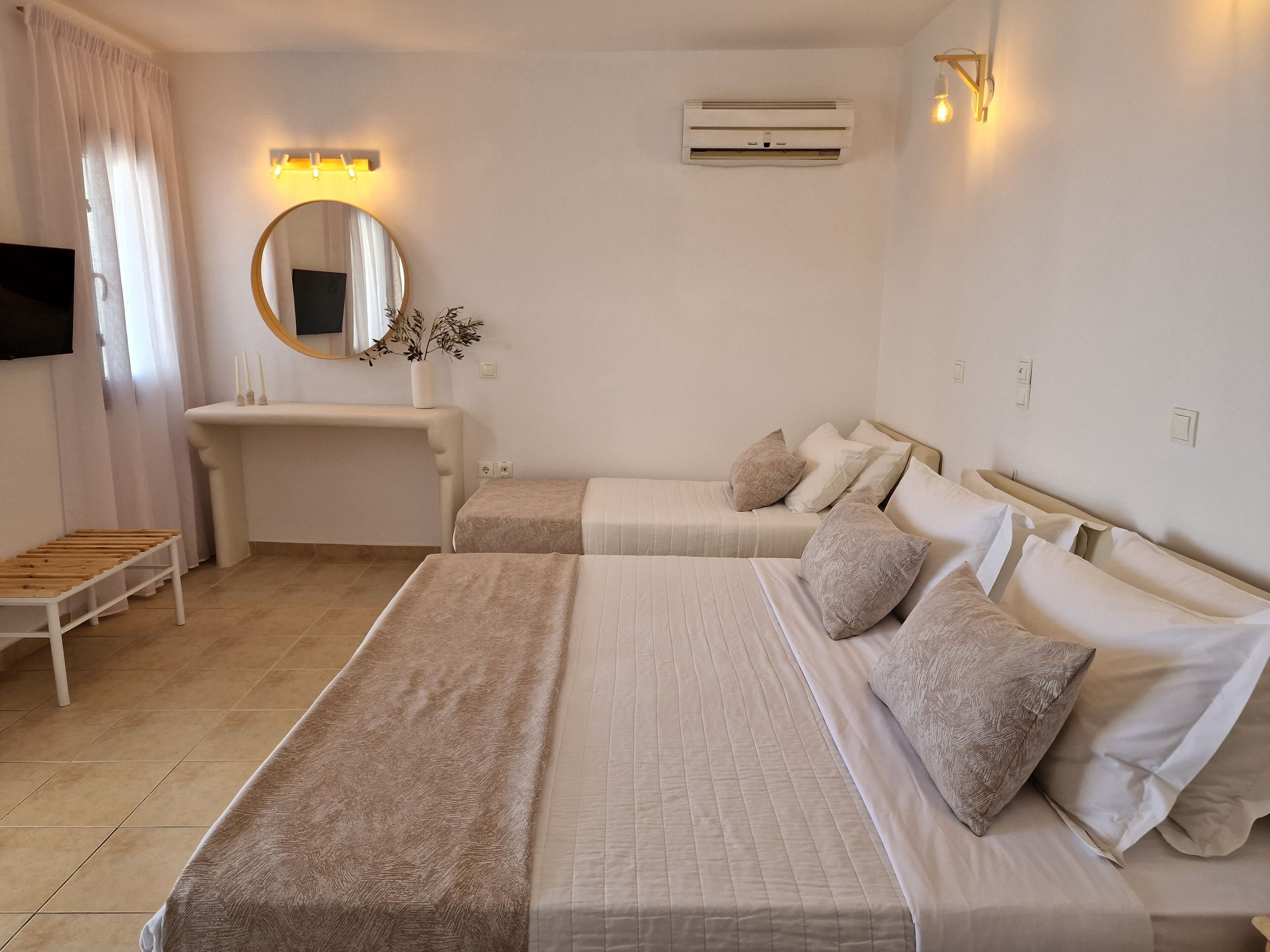 Ein Hotelzimmer mit zwei Betten, einem Schreibtisch, einem Spiegel und einer Klimaanlage.