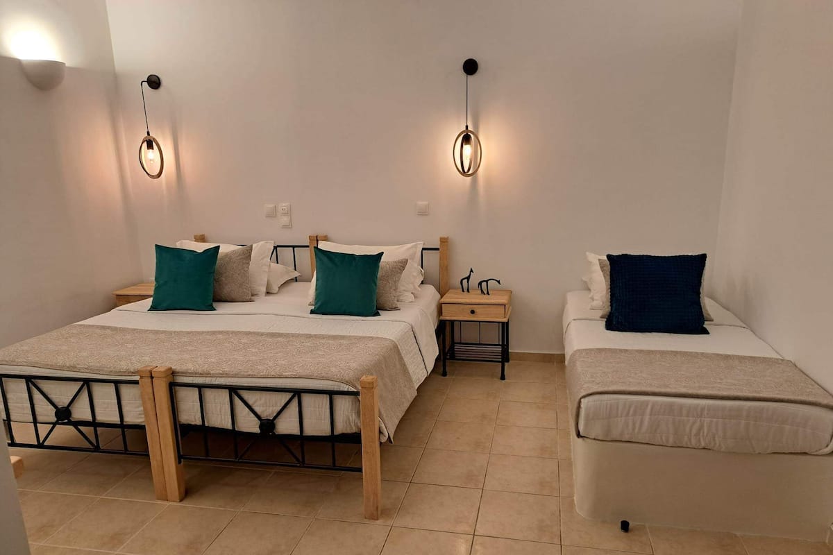Habitación de hotel con dos camas, una mesita de noche e iluminación empotrada.