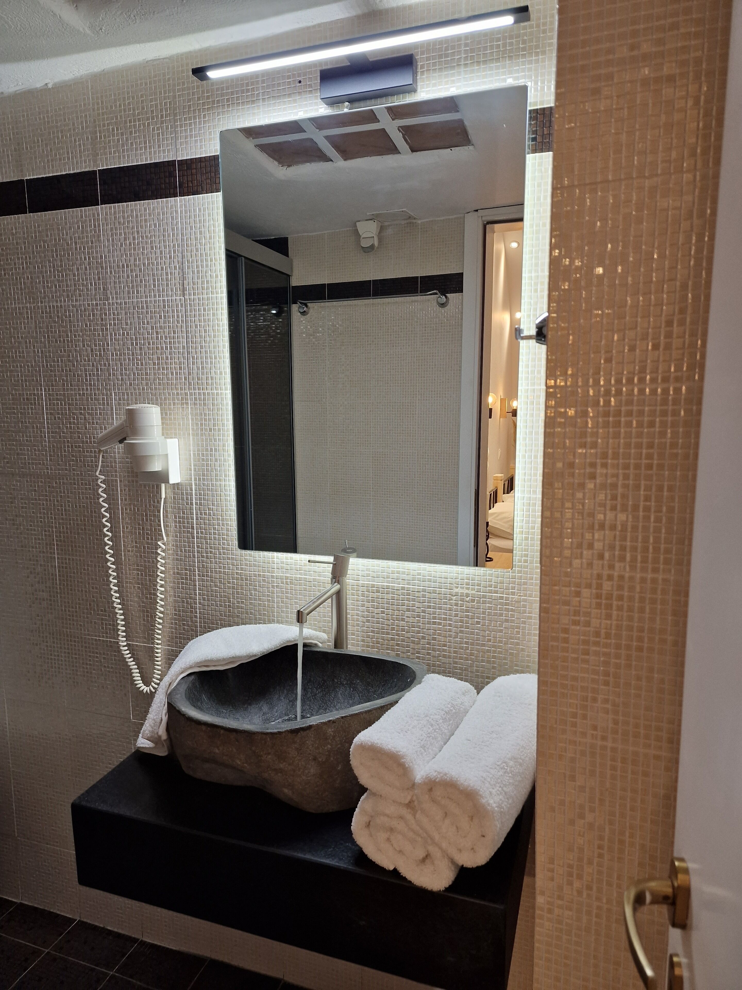 A bathroom with a stone basin, a towel rack, and a mirror.