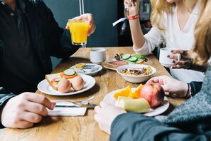 A group of people having breakfast at a wooden table with various food items and drinks. - St Christopher's Berlin Alexanderplatz - Hostel (Berlin)