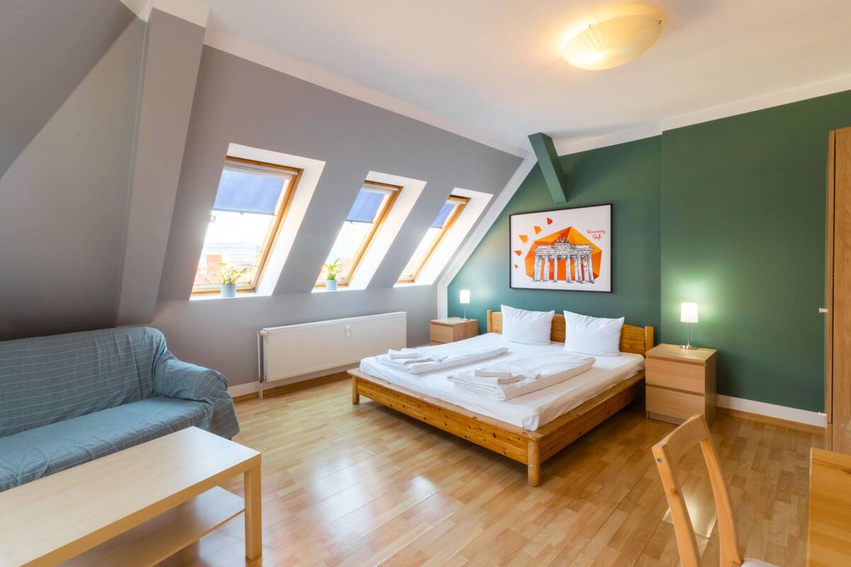 A modern bedroom with a bed, a sofa, a wooden table, and a chair.