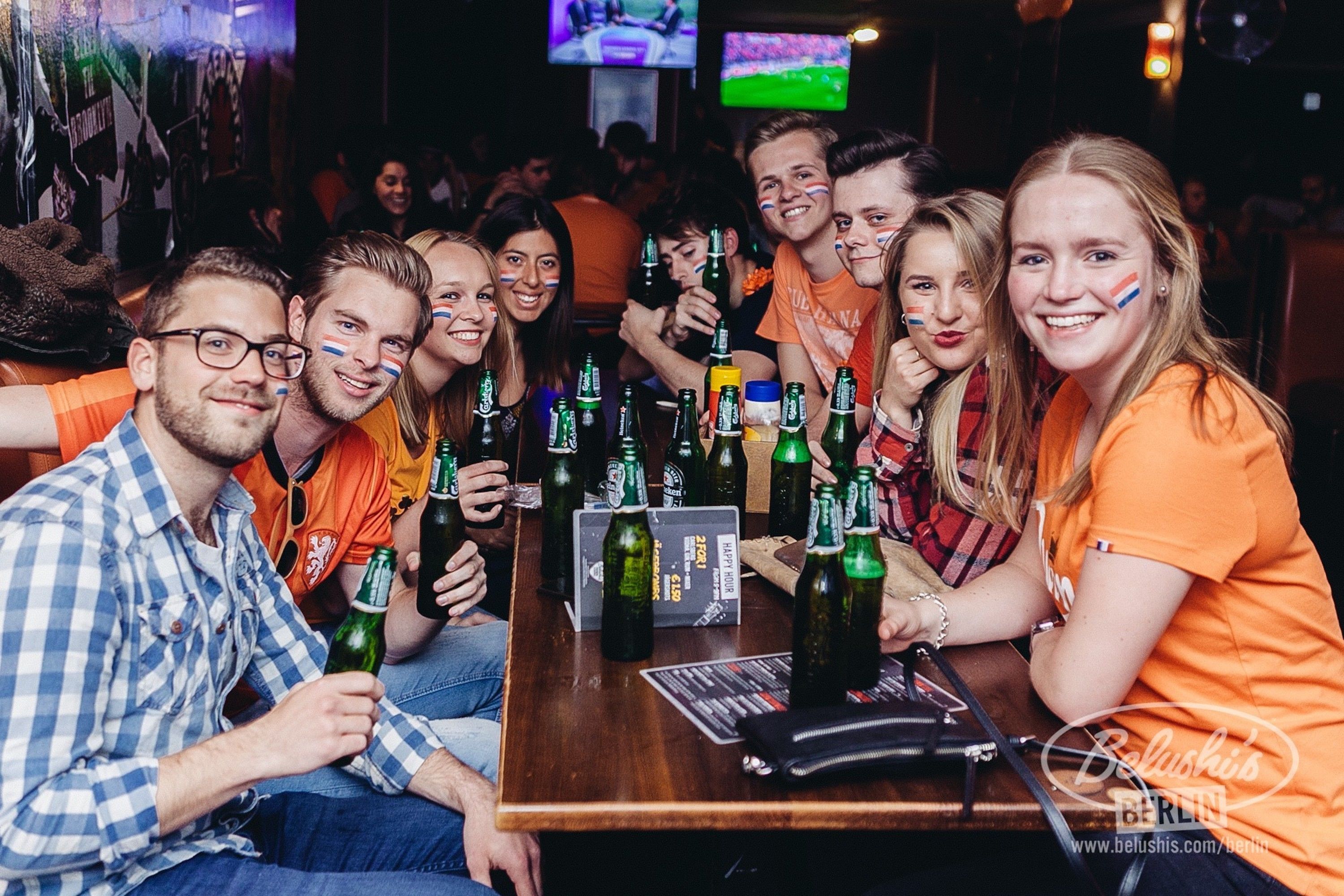 Un grupo de personas en un bar con botellas de cerveza sobre la barra.