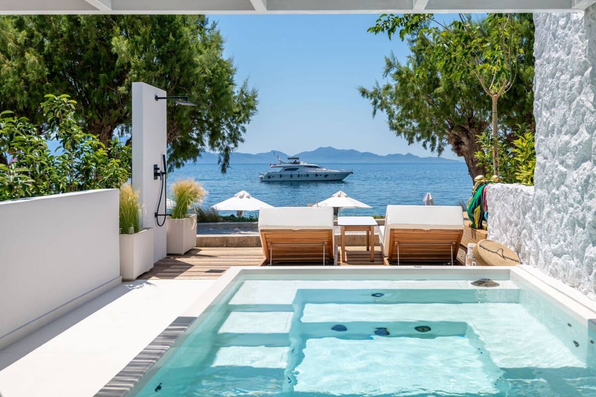 A rooftop pool with a view of the sea and a yacht.