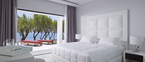 Un dormitorio moderno con una cama grande, una mesita de noche y vista al mar.