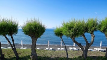 Praia particular, areia preta, espreguiçadeiras, guarda-sóis