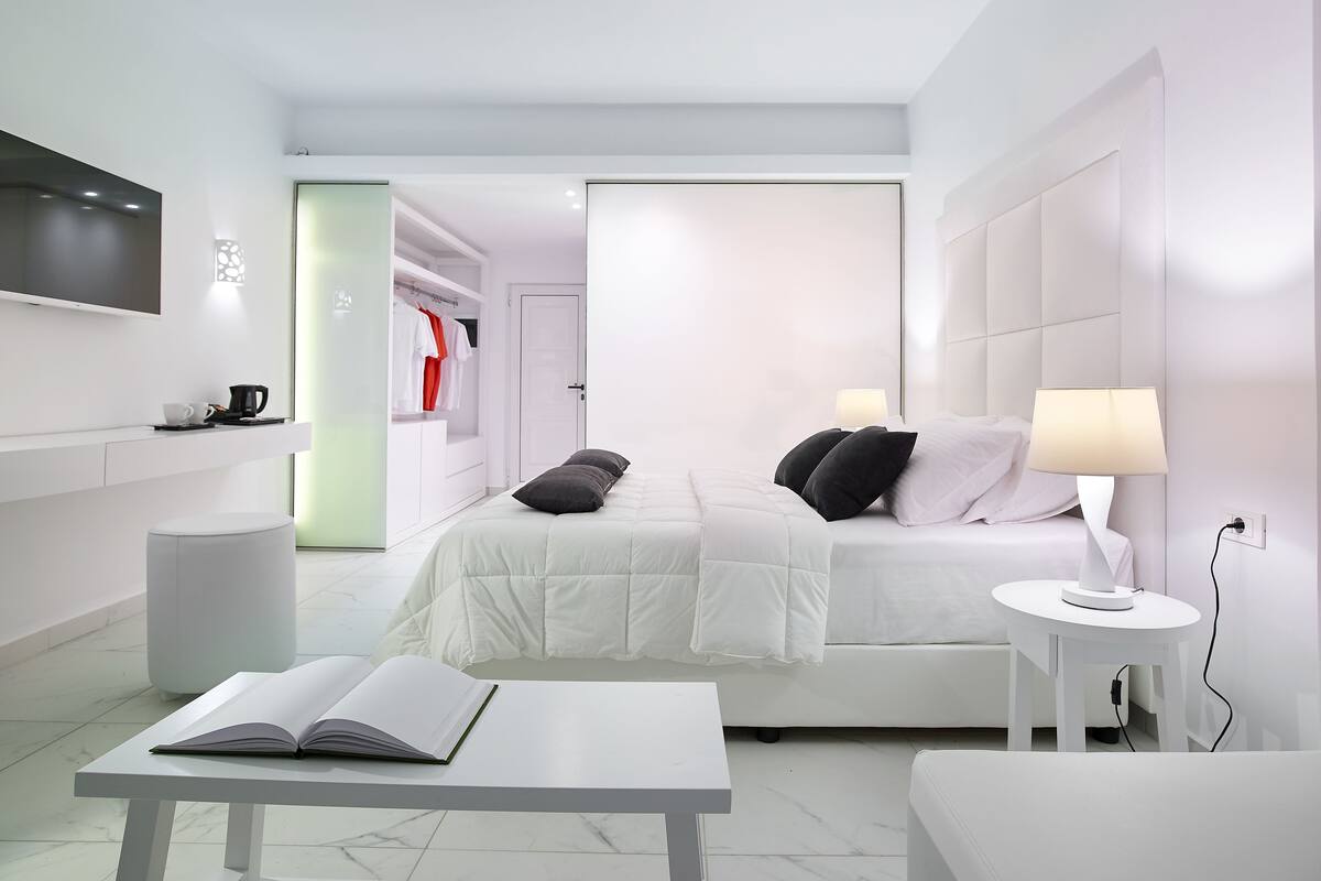 A modern hotel room with a bed, bedside table, and a TV mounted on the wall.