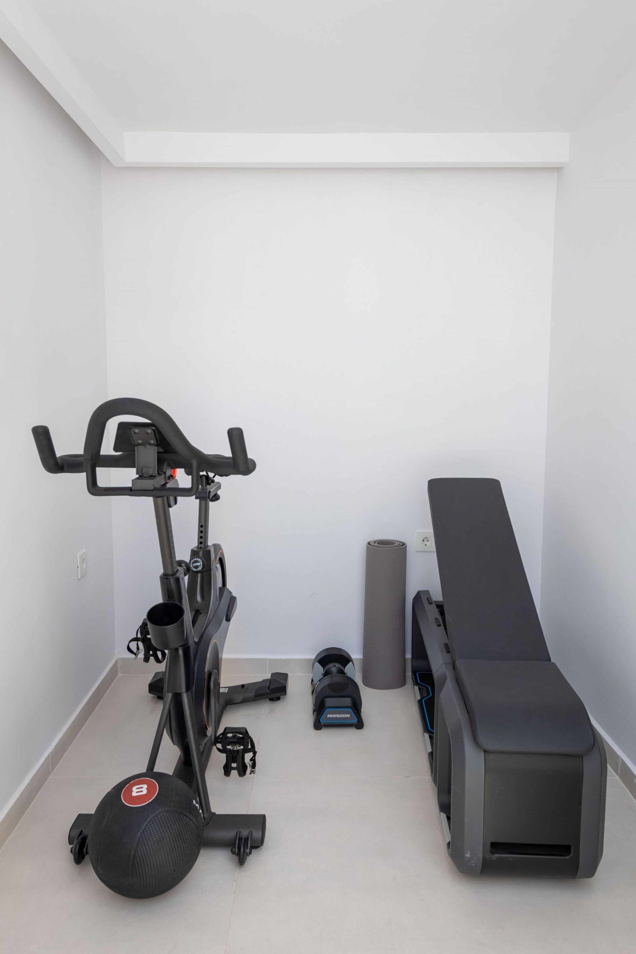 A home gym with an exercise bike, a bench, and a yoga mat.